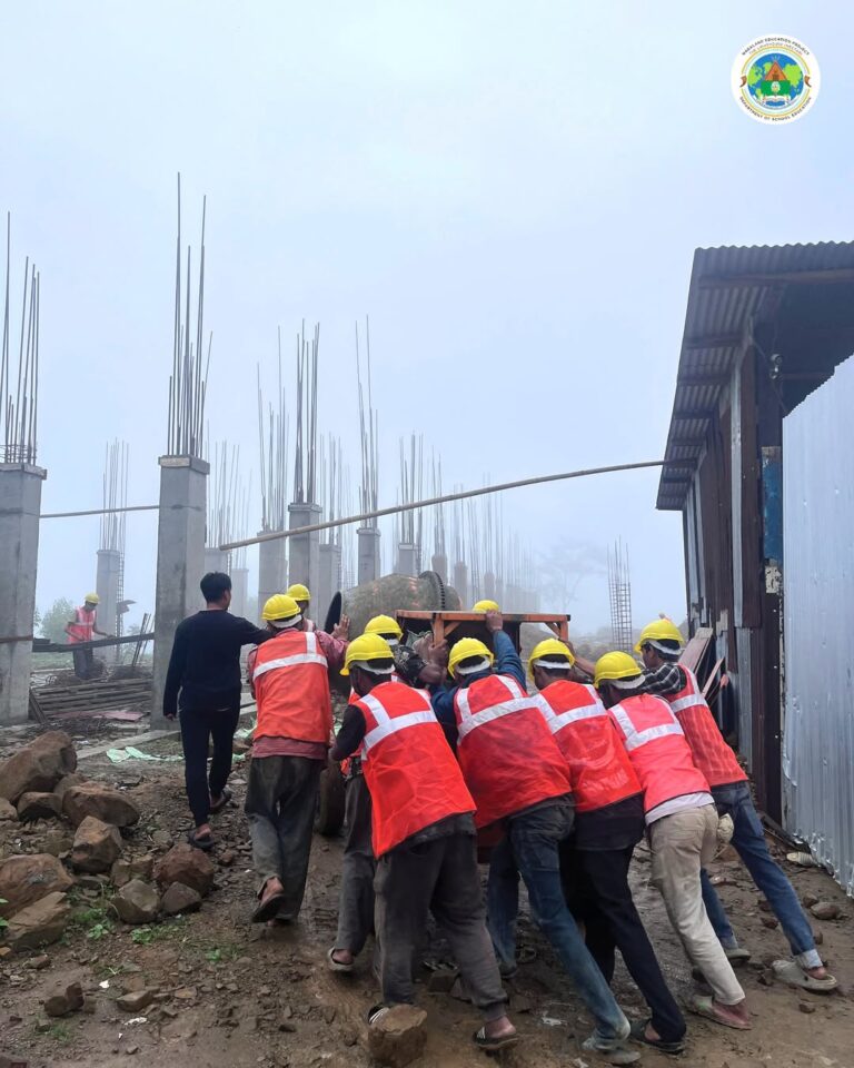 Safety First: Workers Shift Mortar Mixer at GHSS Tseminyu Construction Site